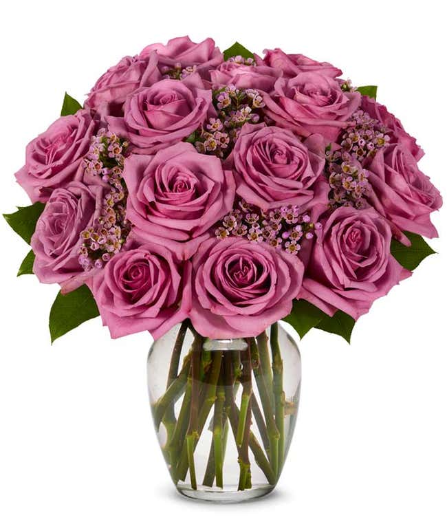 Purple rose arrangement with purple decoration in a glass vase