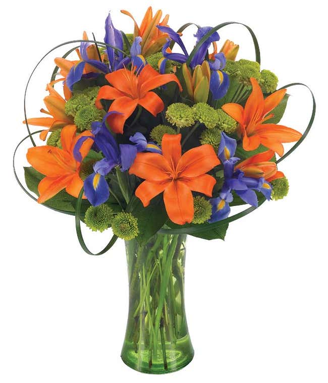 Orange asiatic lilies, iris and green button poms in tall vase