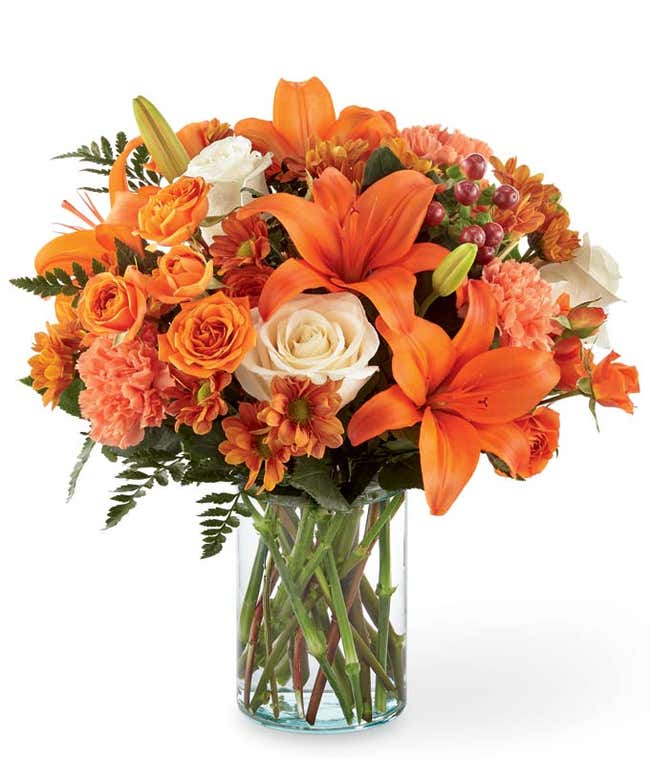 Orange lilies, cream roses and orange roses are arranged for Fall delivery