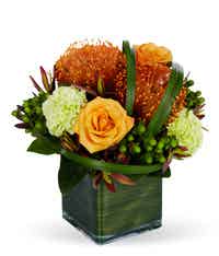 Orange and green floral bouquet in a square vase